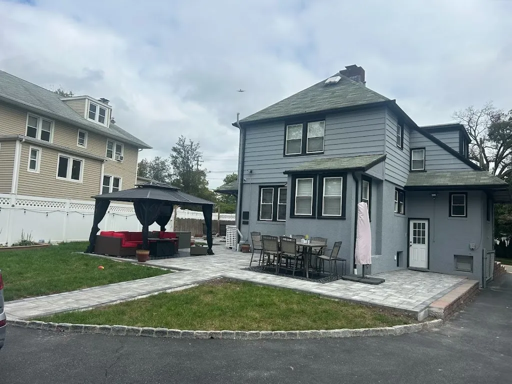 Paver patio with gazebo and connecting walkway behind a gray home