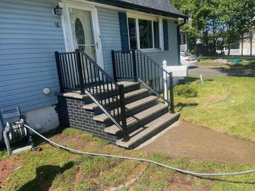 New front steps with charcoal block risers and black railings on a blue house