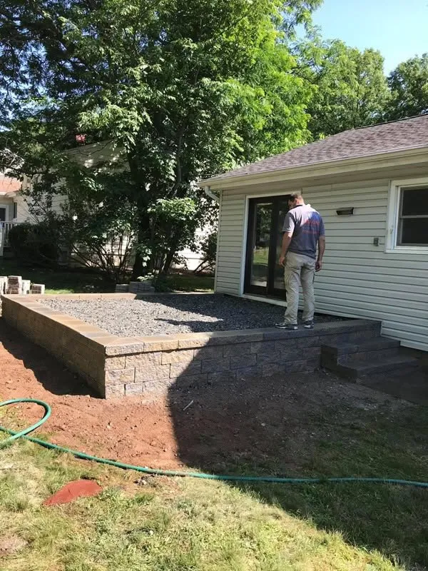 Block retaining wall holding a new gravel terrace behind a ranch home