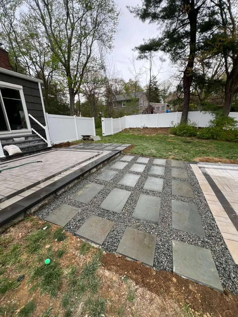 Bluestone stepping stones in gravel between two paver patio areas
