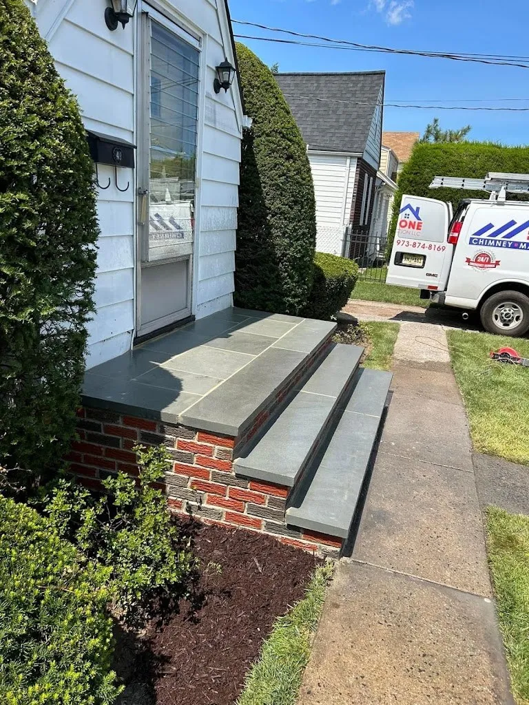 Bluestone steps with red brick risers along a concrete walkway