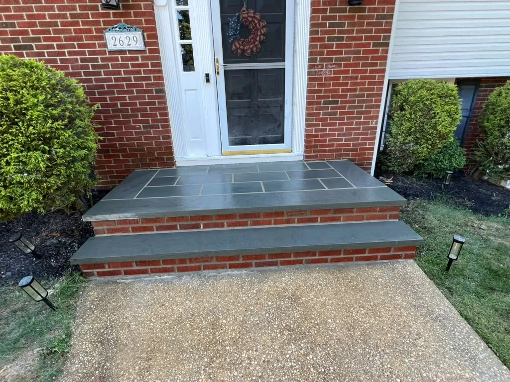 Bluestone front stoop with red brick risers on a brick colonial home