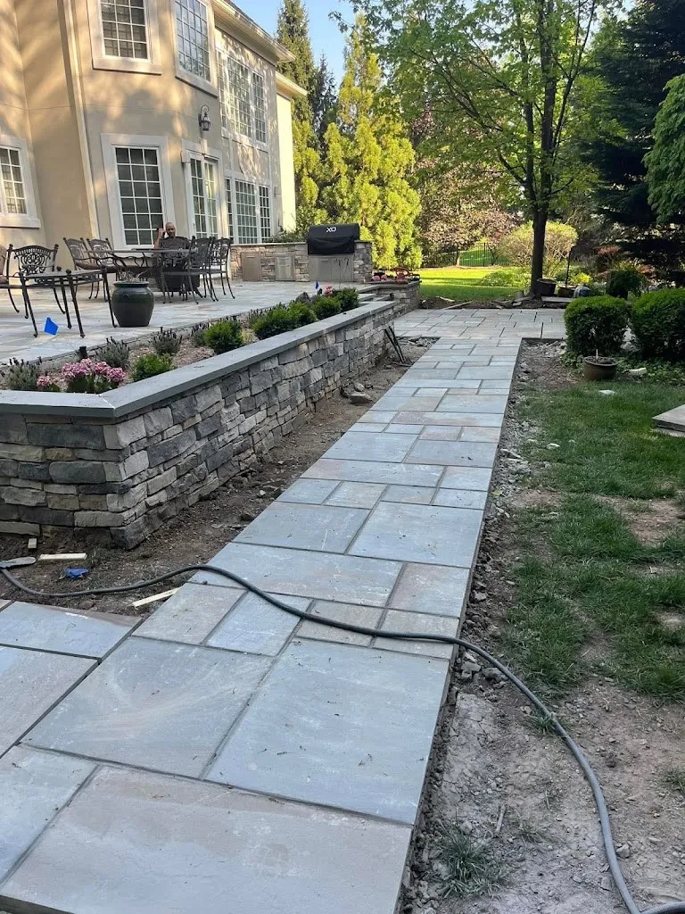 Bluestone walkway beside a stacked stone retaining wall and patio