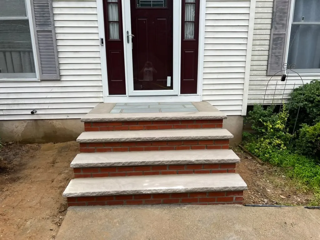 Brick front steps with light stone treads at a white colonial home