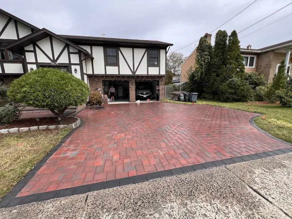 Red brick paver driveway with charcoal border in front of a Tudor home