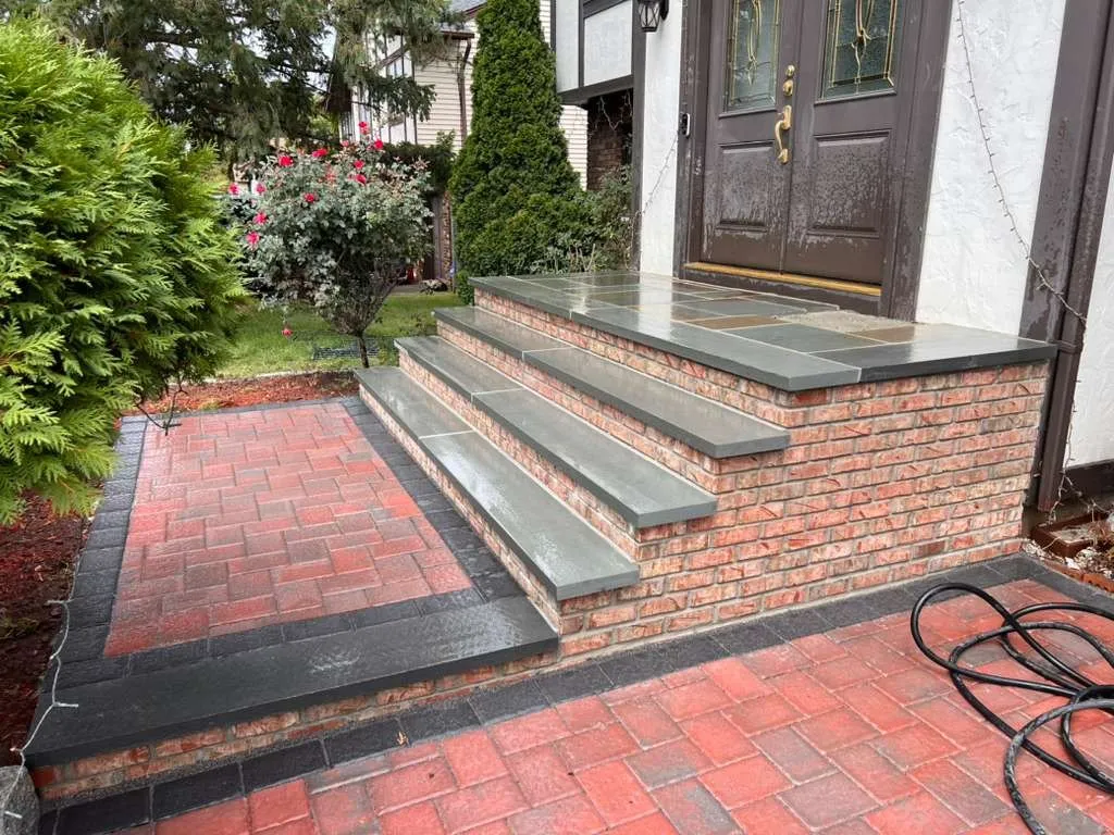 Red brick paver entry with bluestone-capped brick steps at a Tudor-style home
