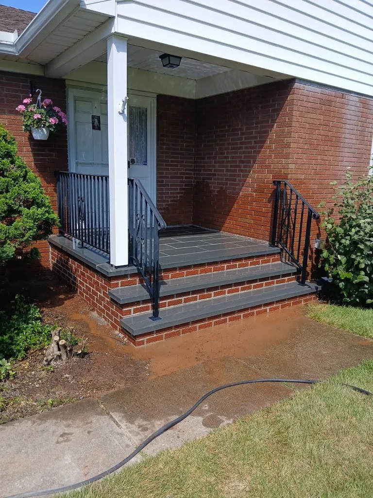Brick steps with bluestone treads and railings at a covered front door