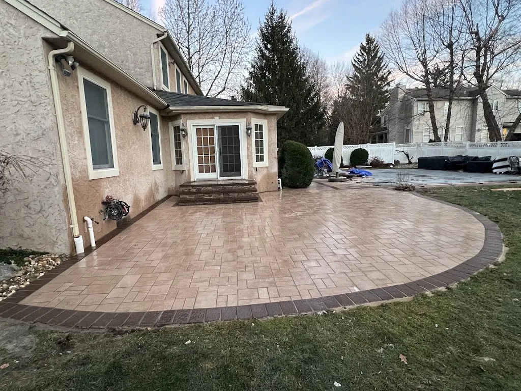 Large circular paver patio with contrasting border behind a home