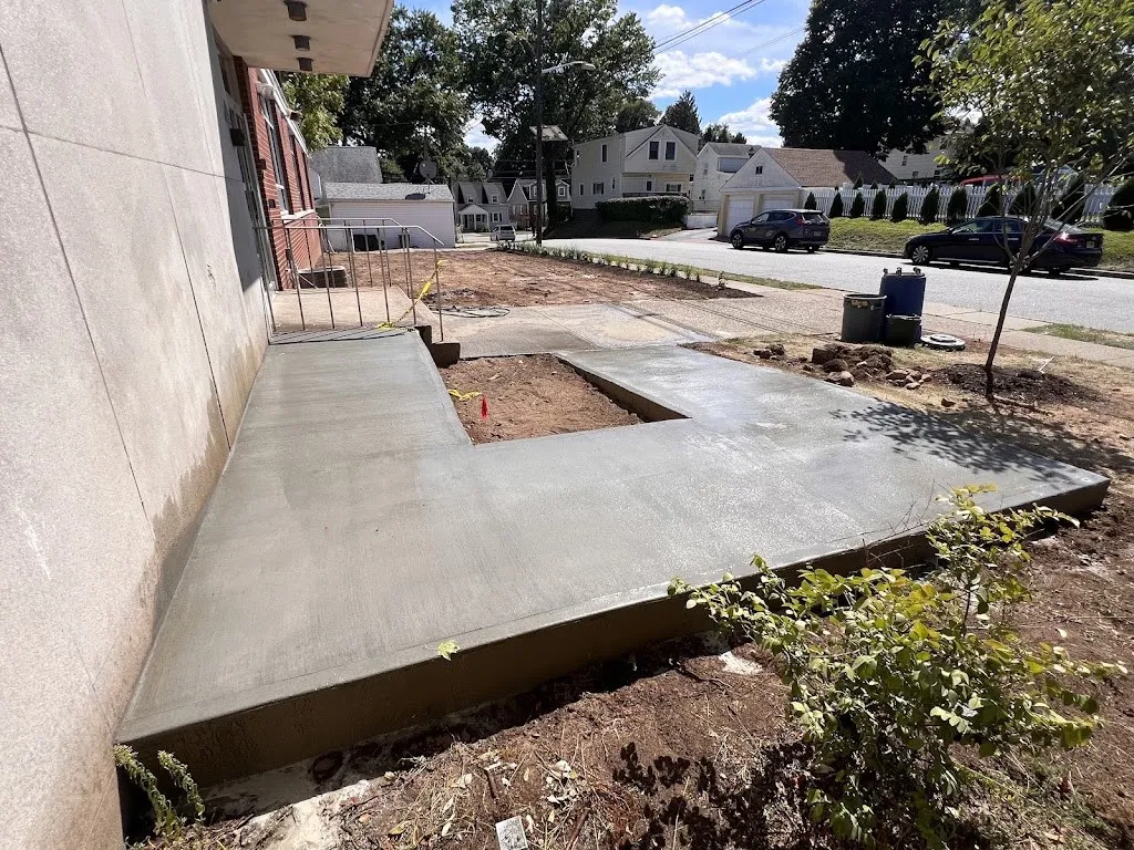 Freshly poured concrete sidewalk and walkway beside a brick building
