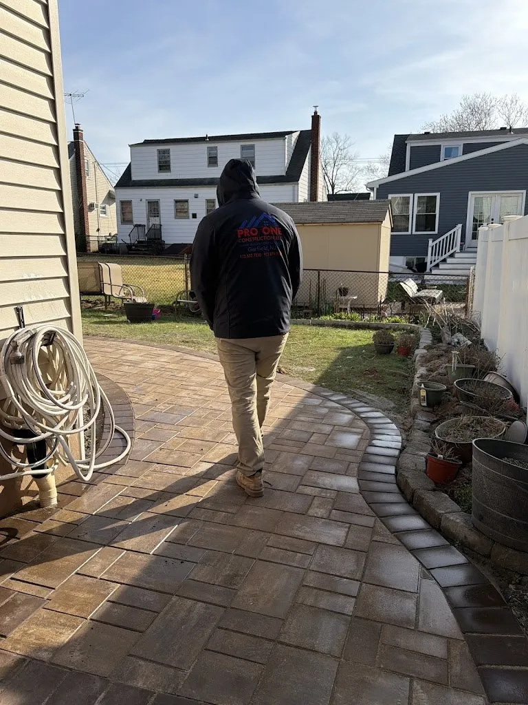 Curved paver walkway through a backyard with a Pro One team member