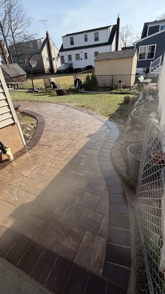Curved paver walkway with border through a backyard