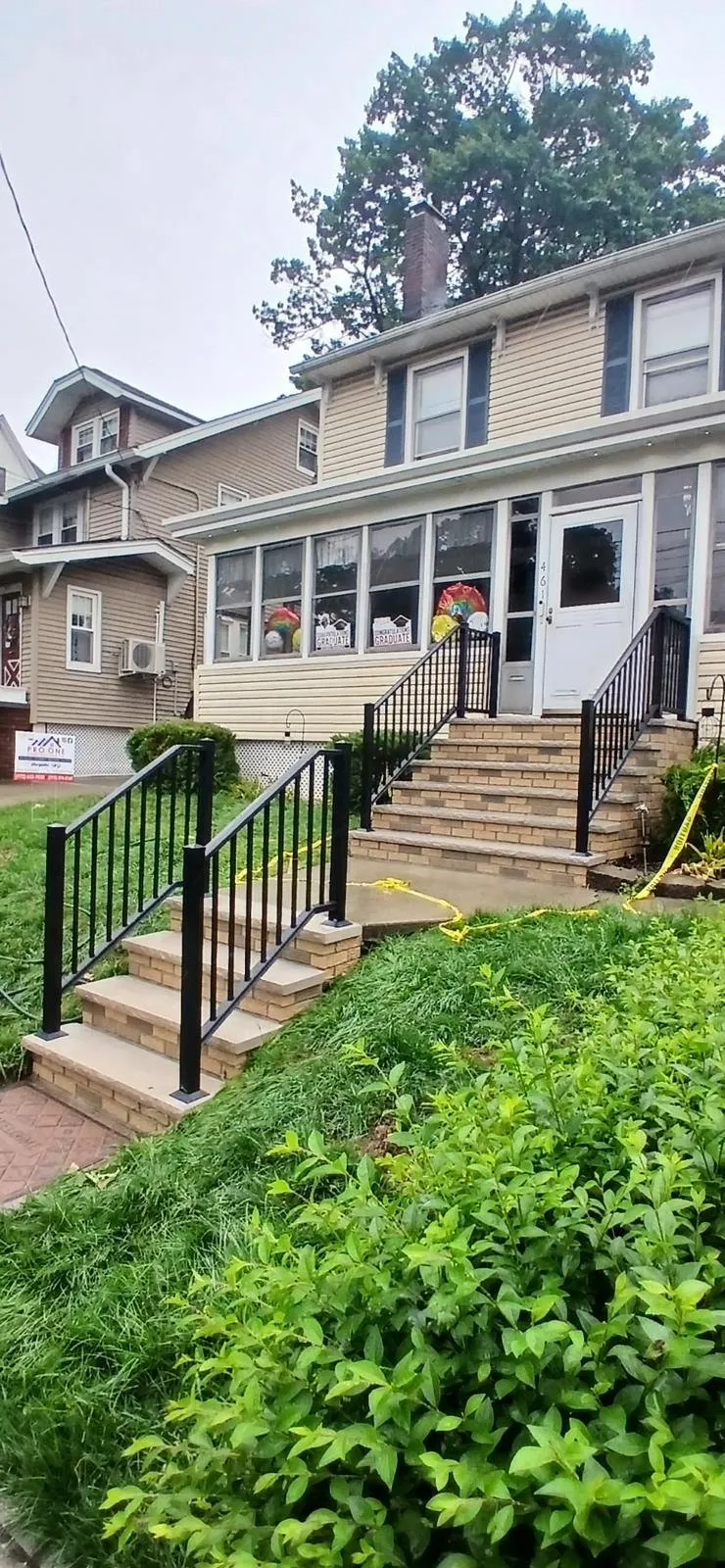 Front steps with black railings climbing a sloped yard to an older home