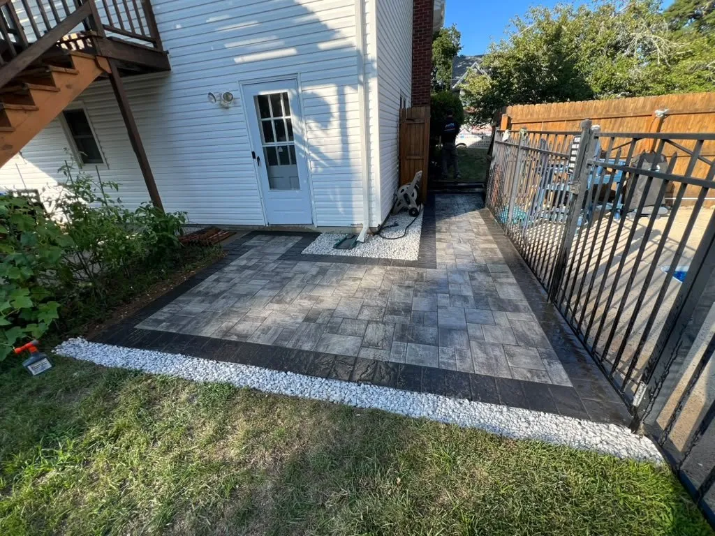 Gray paver side walkway with a charcoal border next to a black metal fence