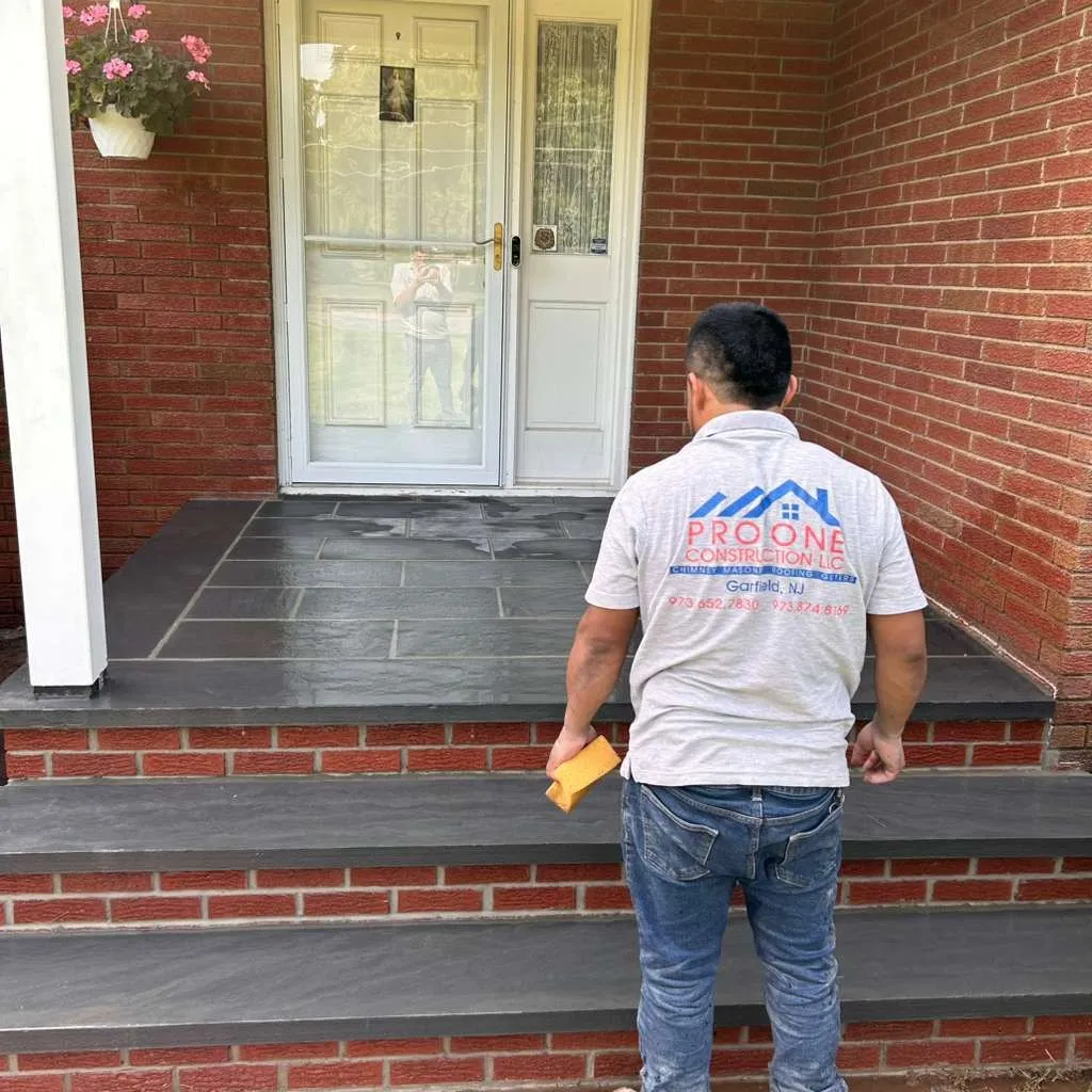 Pro One crew member checking a new bluestone porch with red brick risers
