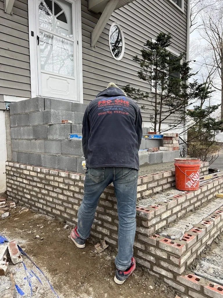 Pro One mason laying brick over a block core for new front steps