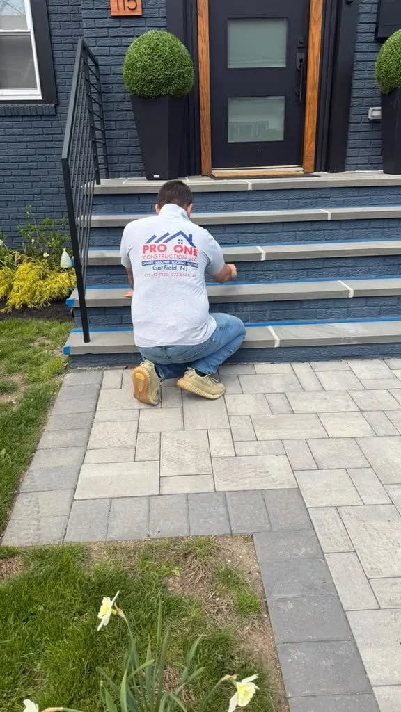 Pro One Construction mason finishing new bluestone front steps above a paver walkway in New Jersey