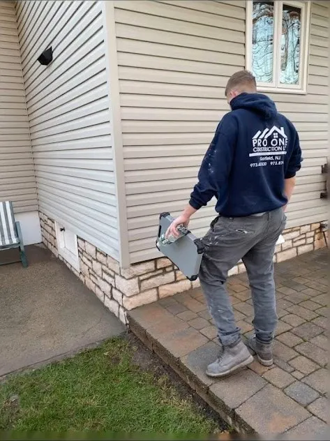 Pro One team member carrying tools past a new stone veneer wall