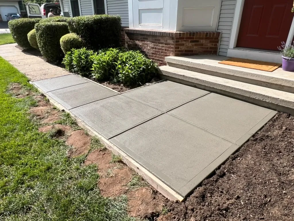 New broom-finished concrete front walkway to a brick front stoop
