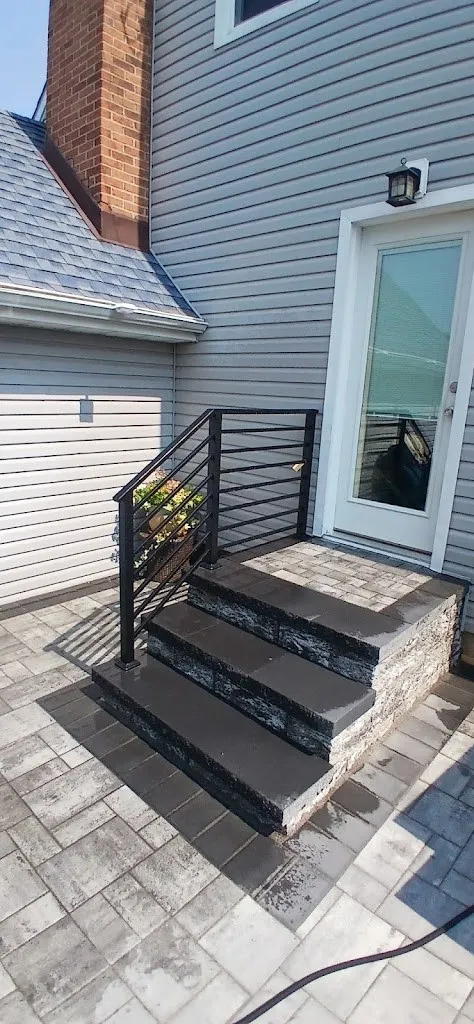 Back steps with stone risers and railing above a new paver patio