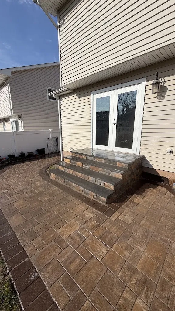 Brown paver patio with steps up to French doors