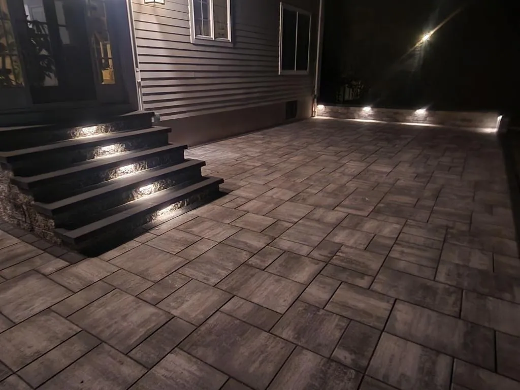 Dark paver patio and steps with built-in LED step lights at night