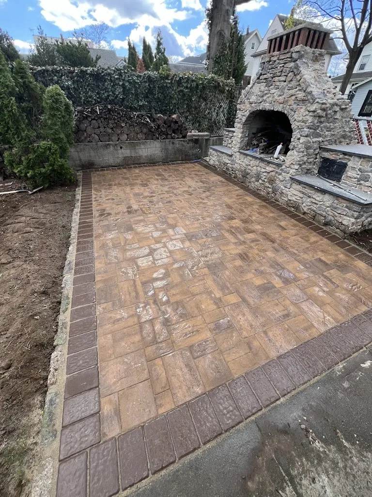 Paver patio with soldier course border leading to a stone outdoor fireplace