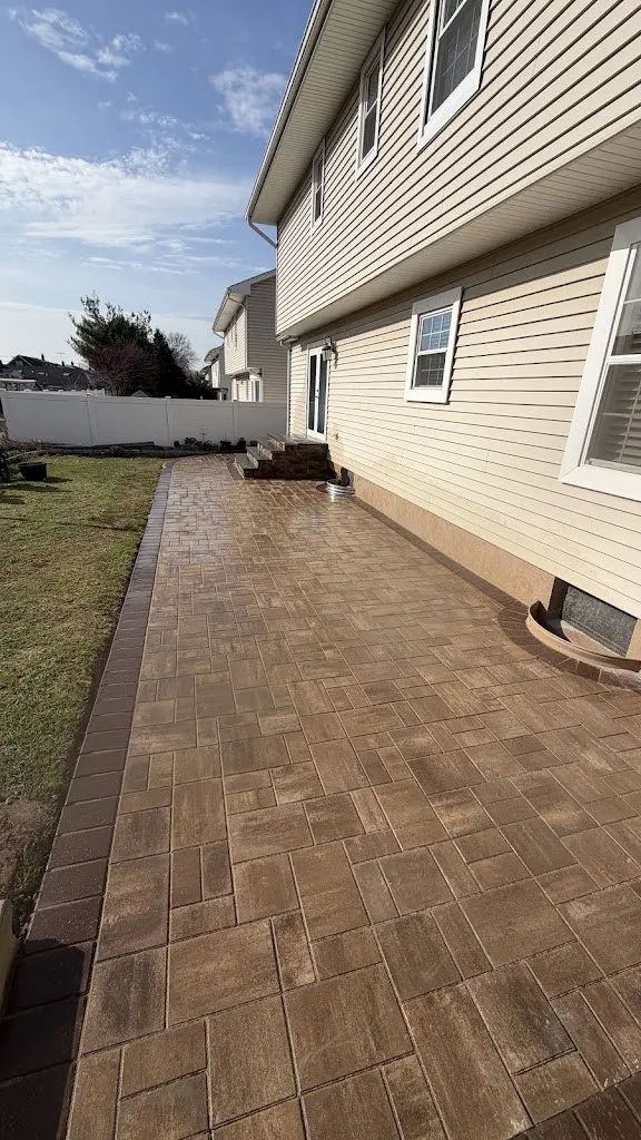 Long paver patio running down a side yard with a dark border