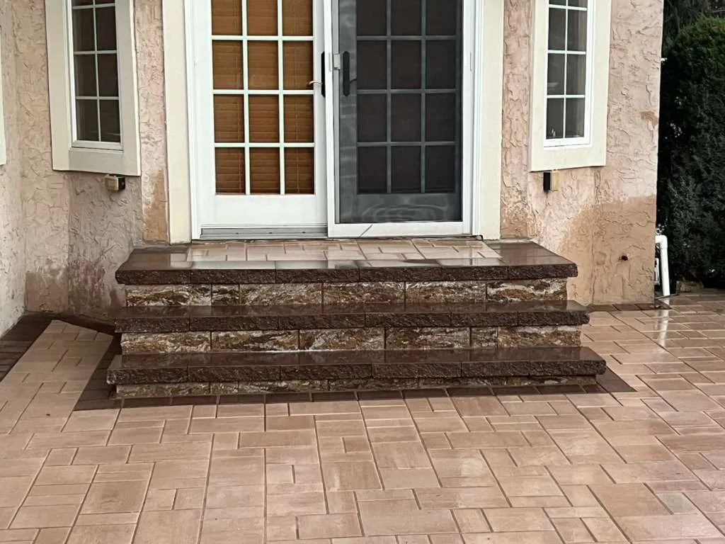 Stone-faced paver steps at French doors opening onto a tan paver patio