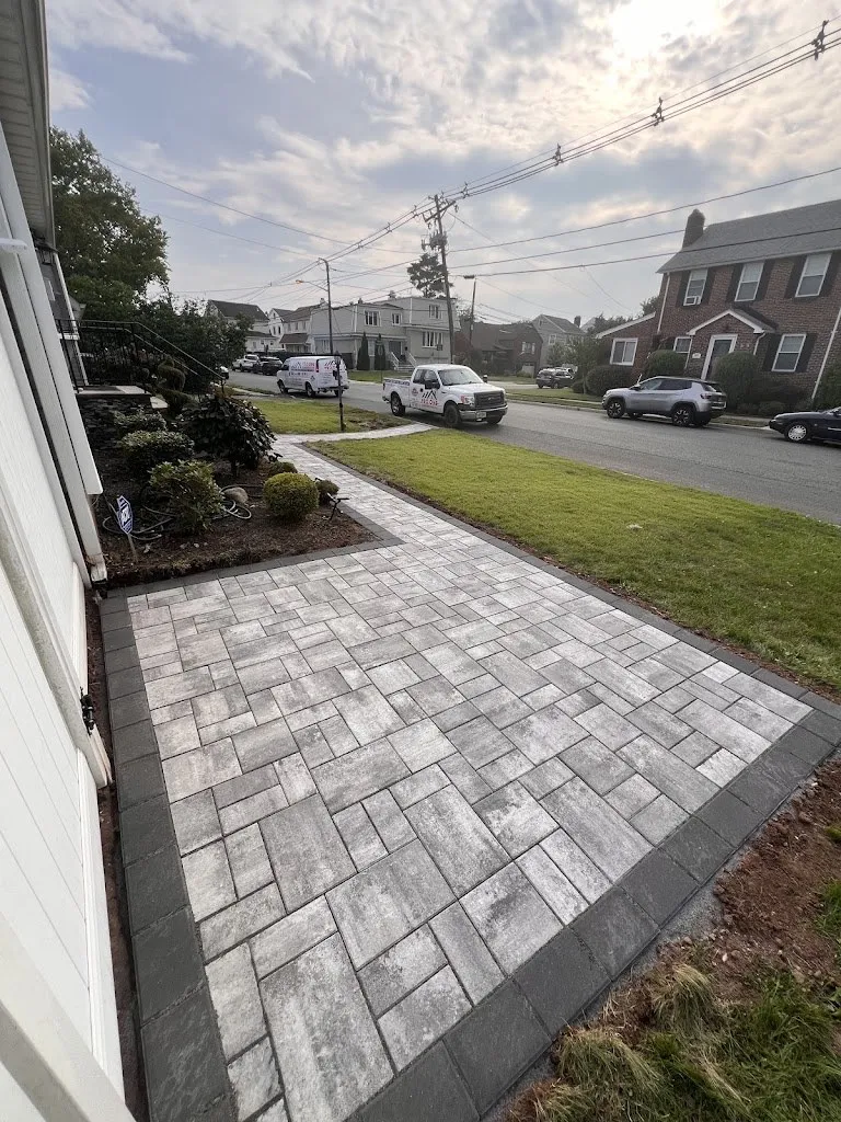 Gray paver walkway with dark border across a front yard