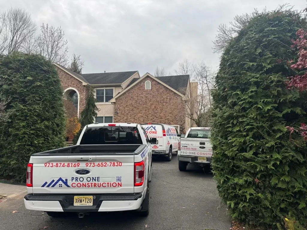 Pro One Construction trucks lined up in a brick home driveway