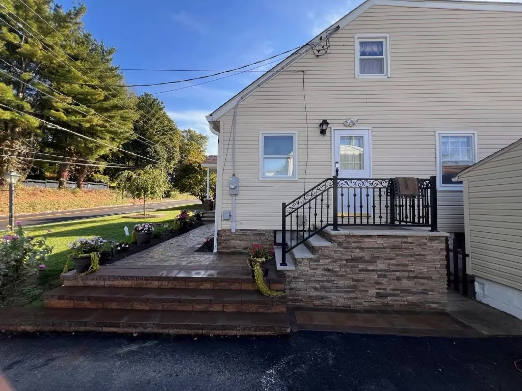 Rear stoop and steps faced in stone veneer with a black railing