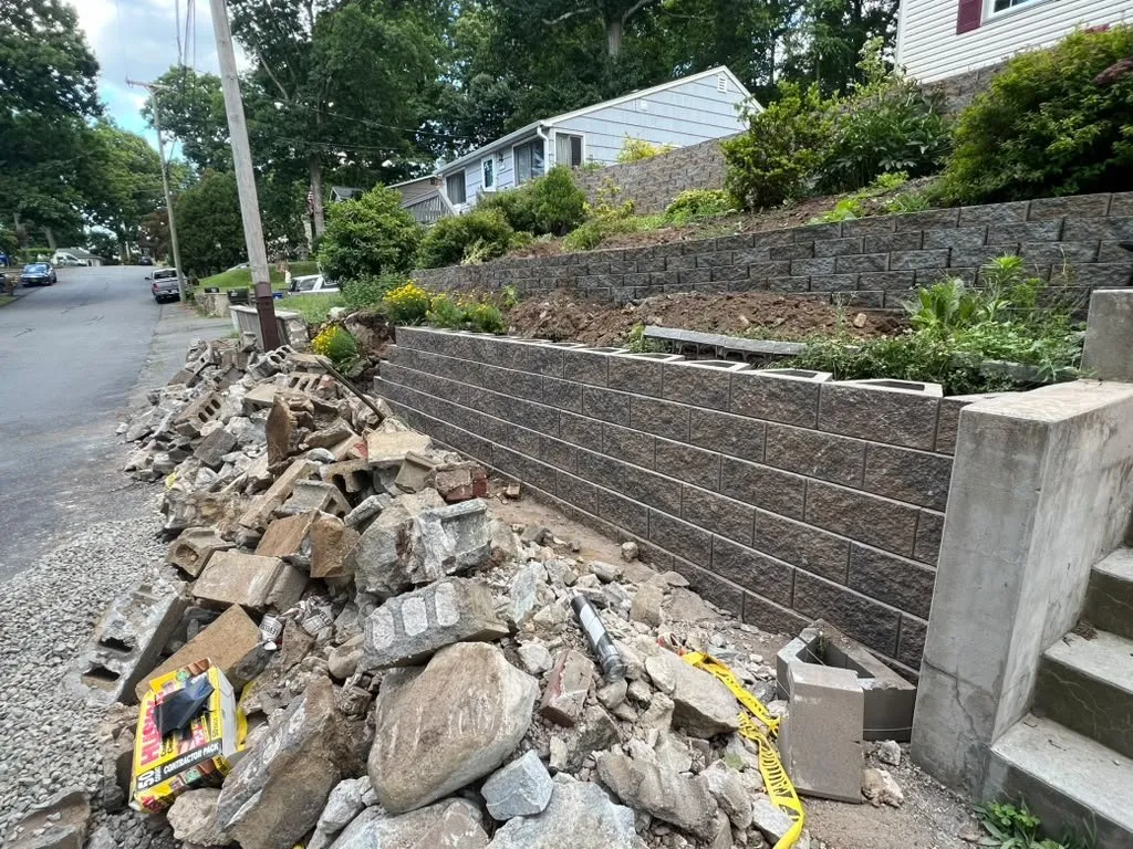 Old stone wall removed beside a new segmental block retaining wall
