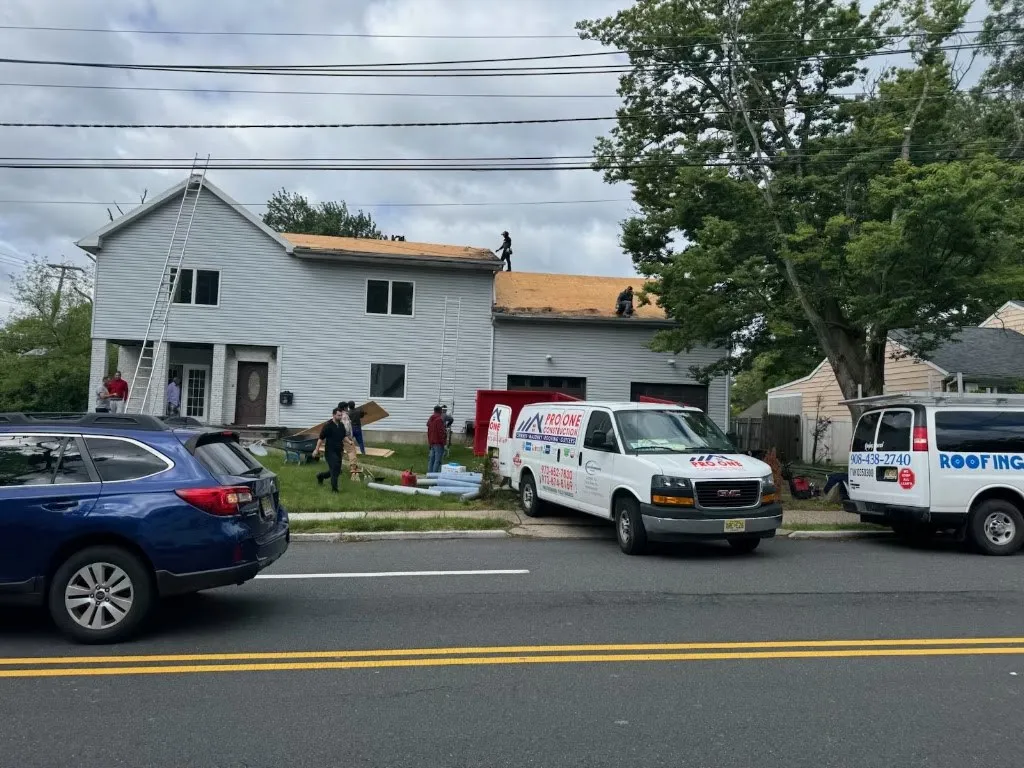 Pro One Construction crew and vans on site during a roof replacement