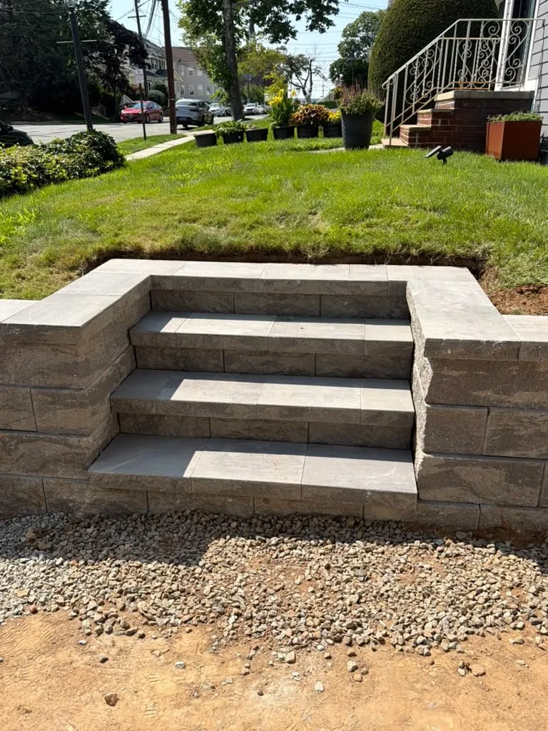 Segmental block steps built into a low retaining wall on a sloped lawn
