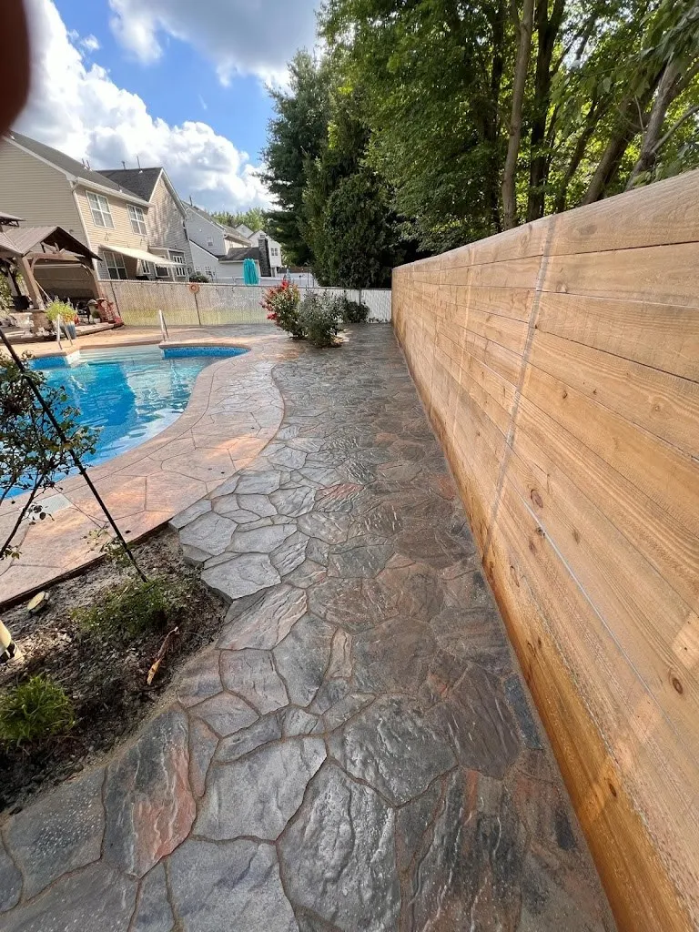 Stamped concrete pool deck in a flagstone pattern along a wood fence