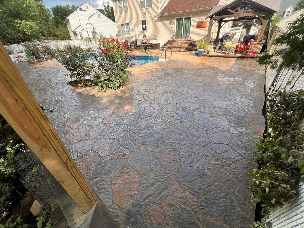 Stamped concrete patio in a flagstone pattern around a backyard pool