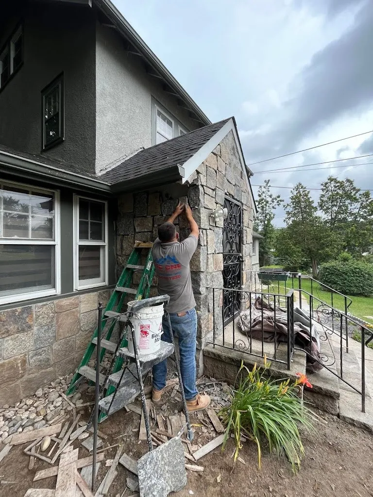 Mason working on a stucco and stone exterior facade