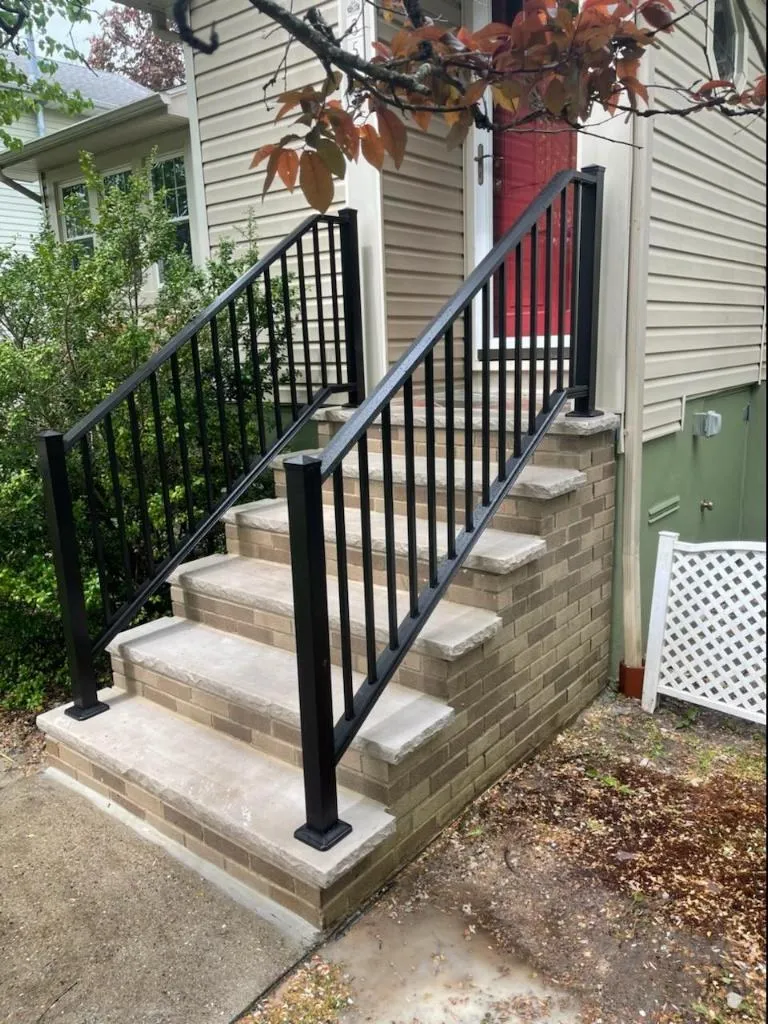 Stone veneer front steps with black aluminum railings