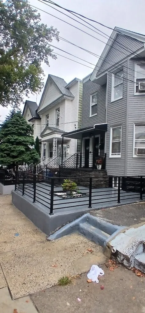 Stone veneer front yard wall with black railing on a city street