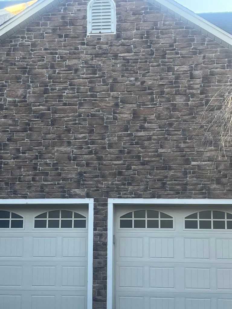 Brown stone veneer on a garage gable wall above two doors