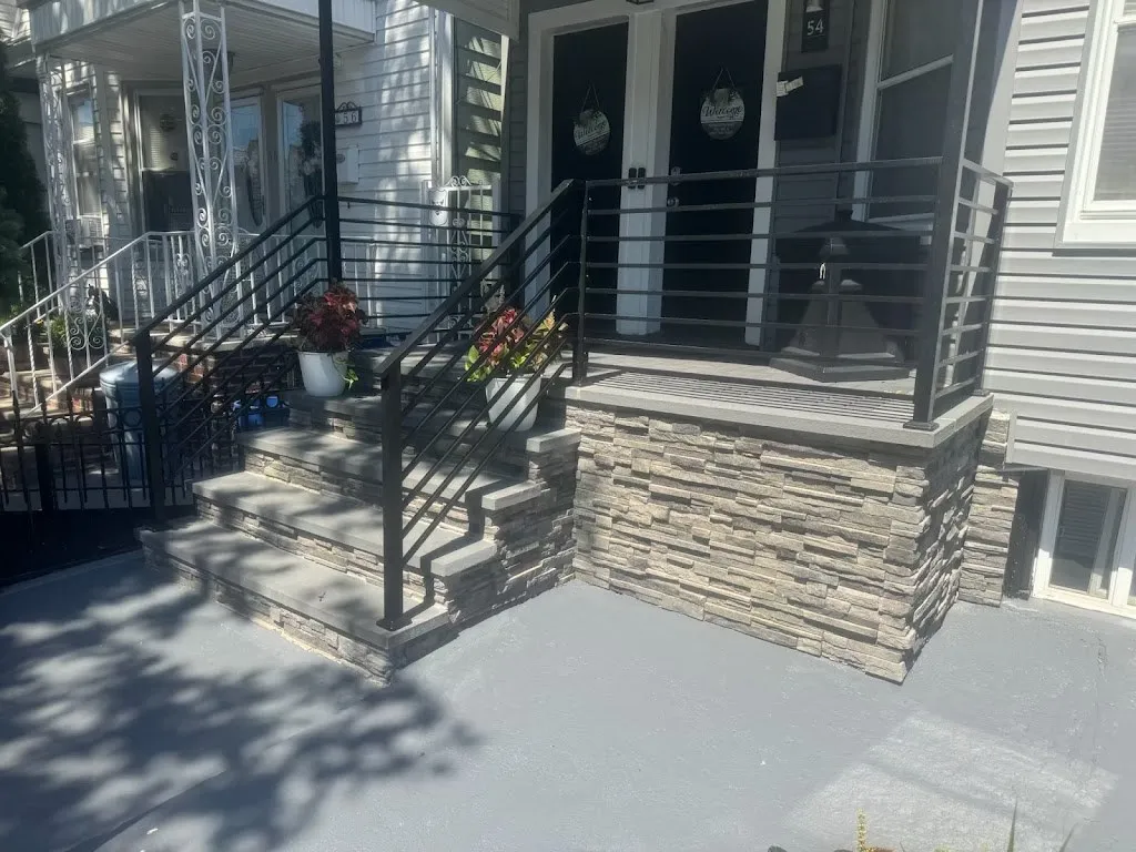 Front porch faced in stacked stone veneer with horizontal black railings