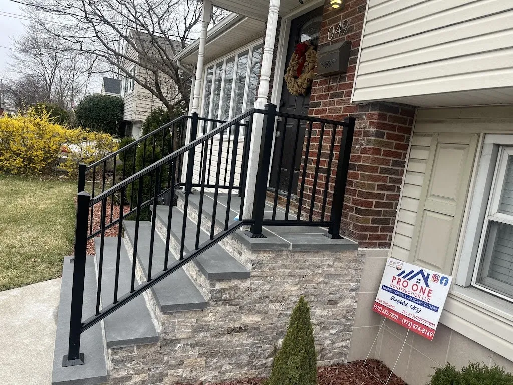 Rebuilt front steps with stone veneer risers, bluestone treads and black aluminum railings