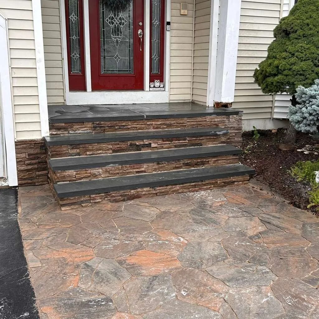 Stacked stone veneer front steps with bluestone treads below a red front door