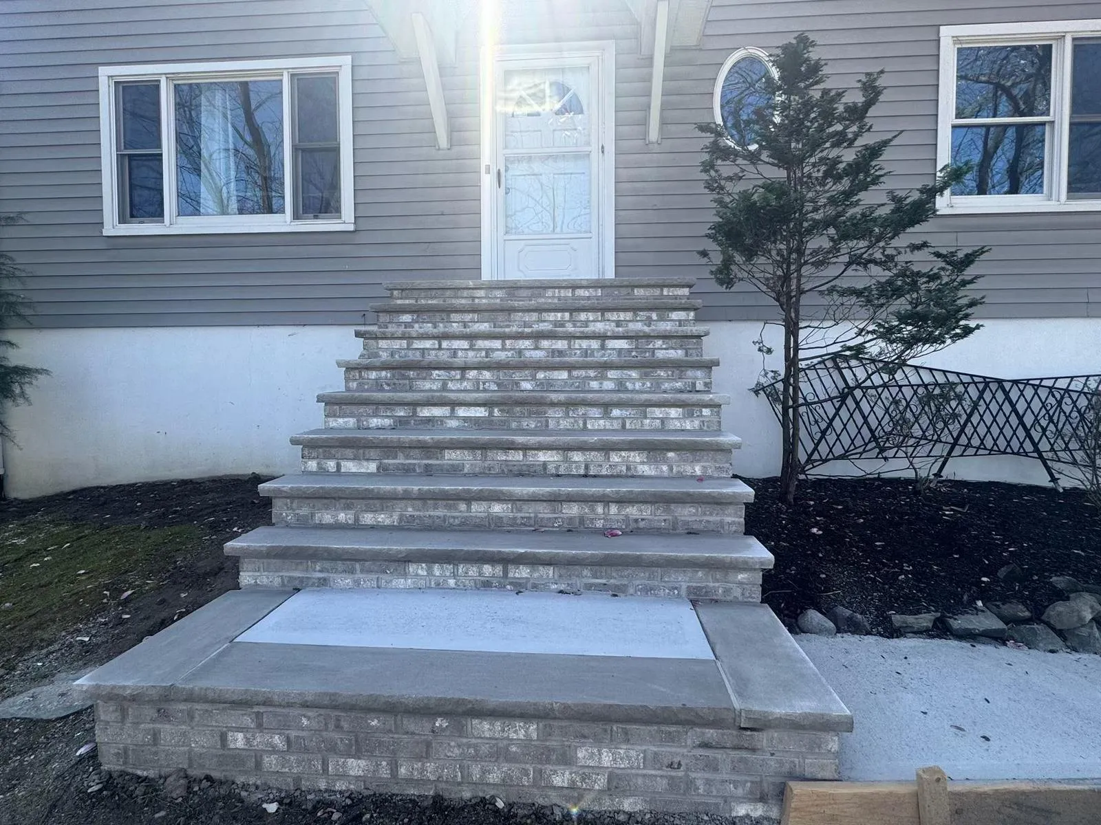 Tall brick front steps with bluestone treads on a gray sided home